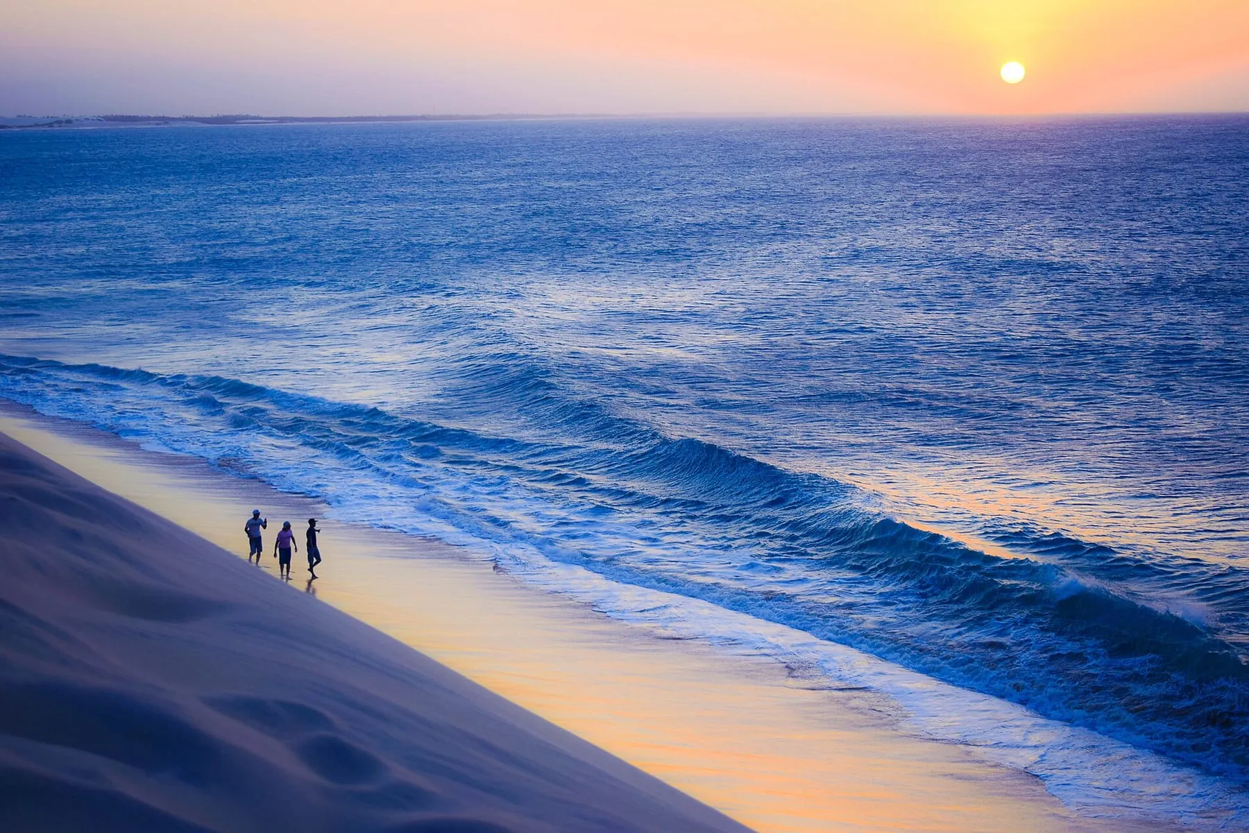 Menschen, die auf der Duna do Pôr do Sol gehen, mit dem Meer von Jericoacoara im Hintergrund